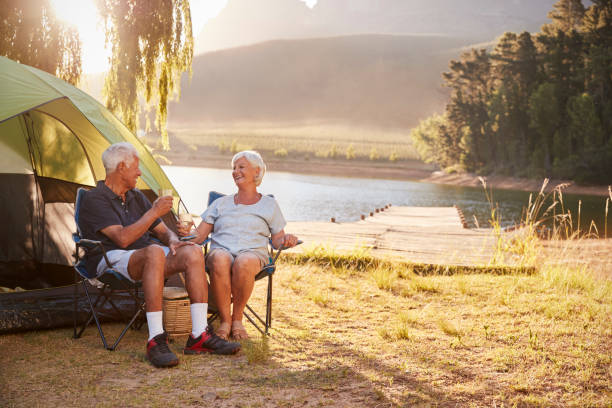 Senior Couple Enjoying Camping Vacation By Lake Making A Toast